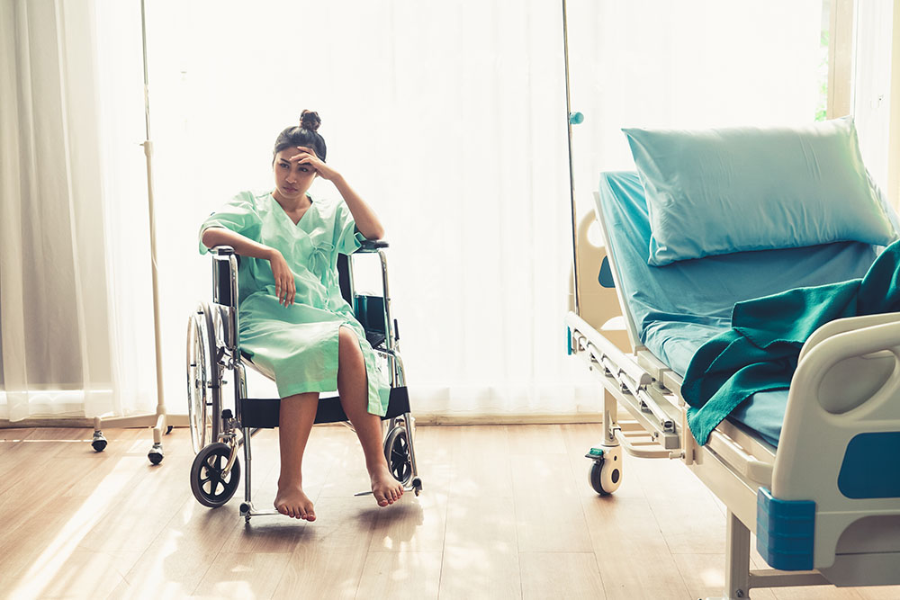 A woman in a wheelchair sitting on the floor of a room.