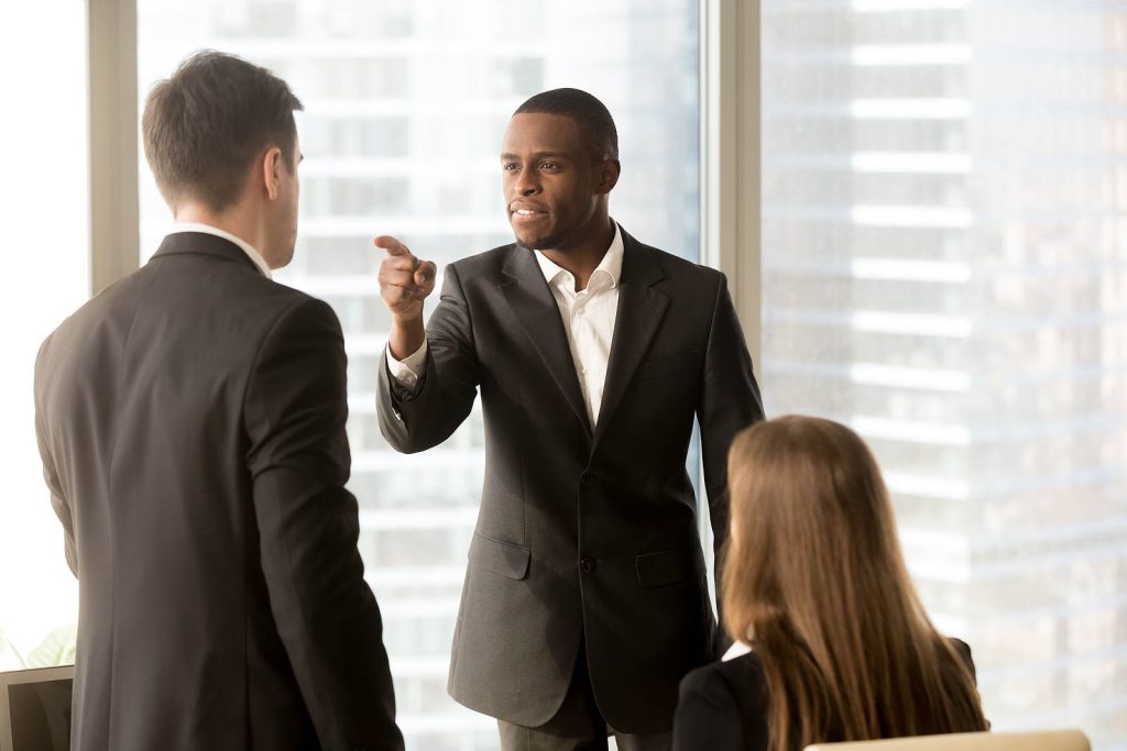 A man in a suit and tie talking to two other people.