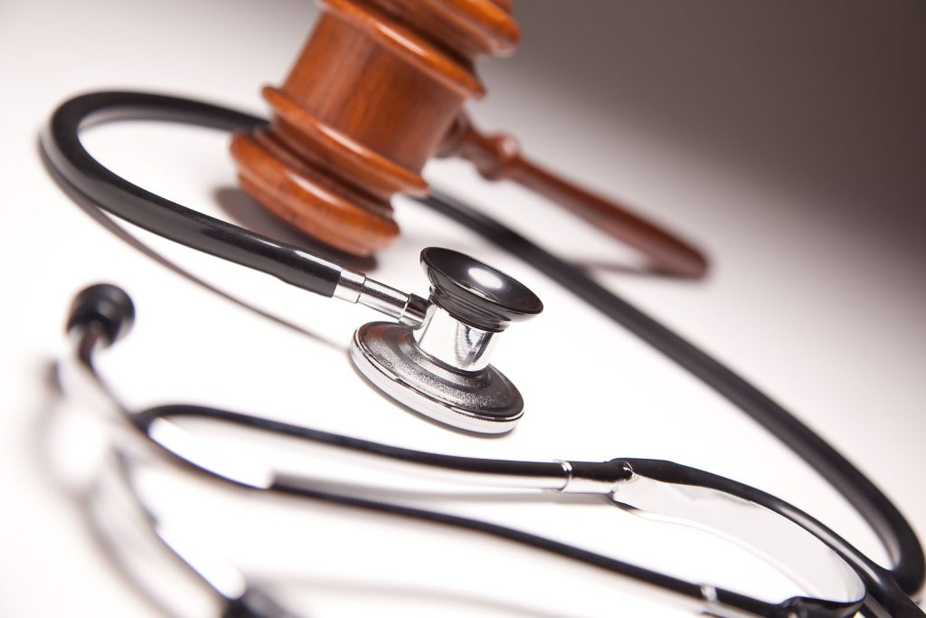 A judge 's gavel and stethoscope on top of a table.