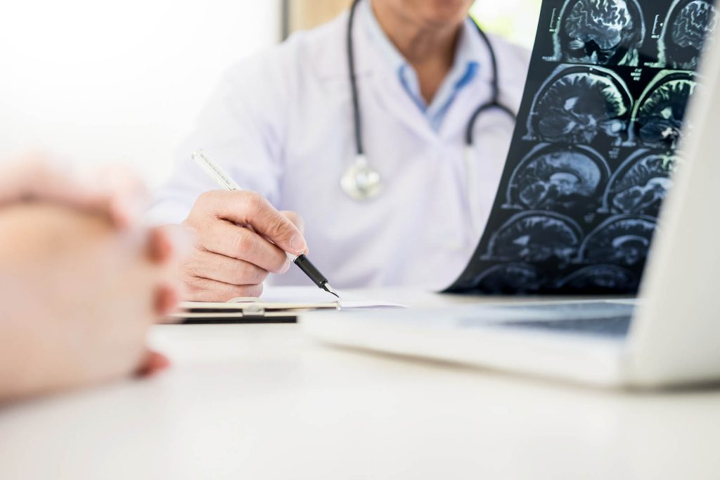 A doctor is sitting at his desk writing on the computer.