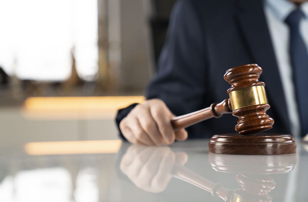 A person is holding a gavel on the table