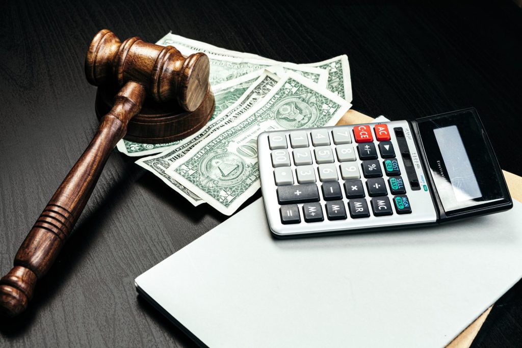 A judge 's gavel, calculator and money on top of a table.