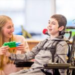 A young boy in a wheelchair holding onto a lego toy