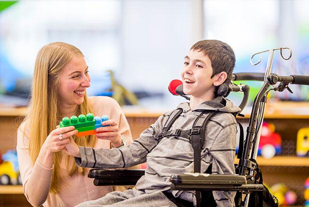 A young boy in a wheelchair holding onto a lego toy